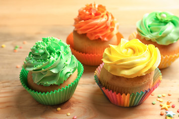 Tasty colorful cupcakes on wooden table