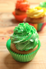 Tasty colorful cupcake on wooden table