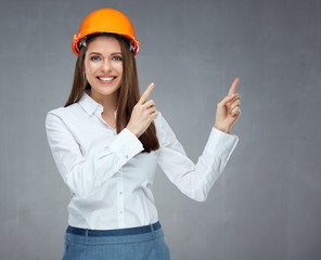 Smiling businesswoman wearing builder helmet pointing finger