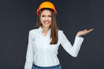 Businesswoman wearing builder helmet presenting empty hand.