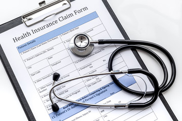 Health insurance for reception at the doctor. Document, stethoscope, pad on white background top view