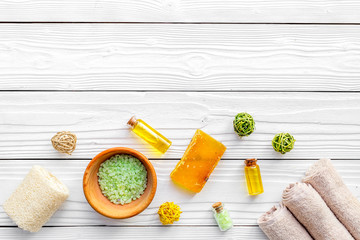 Foot spa cosmetics. Spa salt, oil, soap and towel on white wooden background top view copyspace