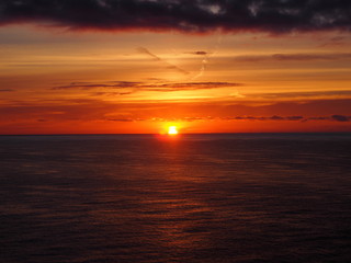 Naklejka na ściany i meble Ein wunderschöner Sonnenuntergang, der Himmel orange und das Wasser blau.