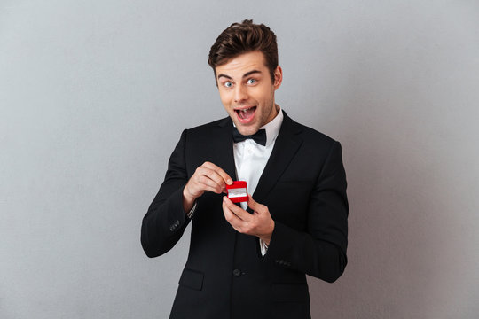 Excited man in official suit holding box with proposal ring.