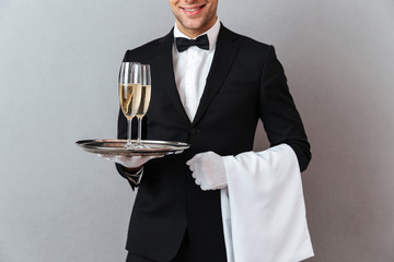 Cropped image of waiter holding glasses of champagne and towel. © Drobot Dean