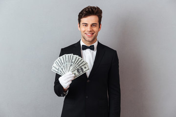 Smiling young waiter holding money.