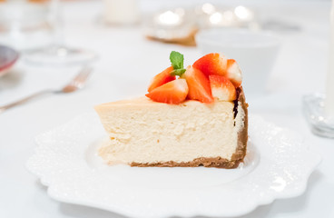 Cheesecake with strawberries and mint leaves on a white plate