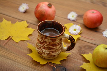 A cup of cocoa, leaves, an apple and a pomegranate - an autumn still life.