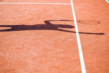 Sunny tennis. Shadow of young woman playing tennis on the tennis court.