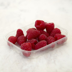 Fototapeta na wymiar Raspberries in Plastic Container on Marble Background Square