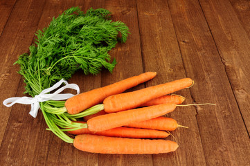 Fresh raw carrots with tops on a rustic wood background