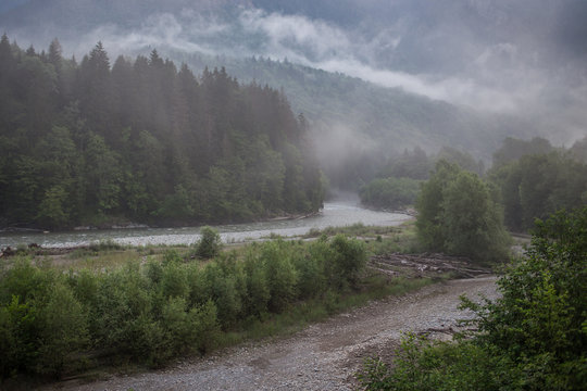 Fototapeta Rapid mountain river and a forest covered with fog