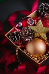 Composition with Christmas decorations in golden box on black background