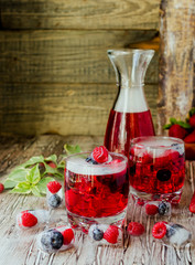Summer berry lemonade with frozen berries on a wooden rustic table, selective focus