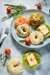Bagels with salmon, vegetables, cream-cheese on grey concrete background