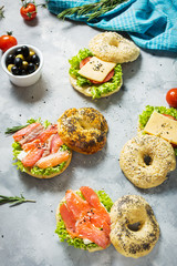 Bagels with salmon, vegetables, cream-cheese on grey concrete background