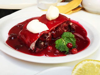 A fresh slice of cherry pie with cherry jam on a white plate. 