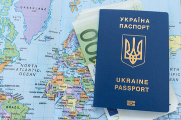 Ukrainian travel passport on a world map with euro banknotes
