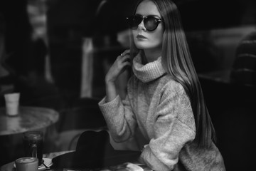 portrait of a young beautiful fashionable woman wearing sunglasses. A model in a stylish wide-brimmed hat. Harmoniously similar clothes in gray tones. Uleach style of shooting. Women's fashion.