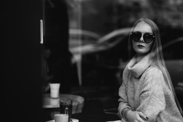 portrait of a young beautiful fashionable woman wearing sunglasses. A model in a stylish wide-brimmed hat. Harmoniously similar clothes in gray tones. Uleach style of shooting. Women's fashion.
