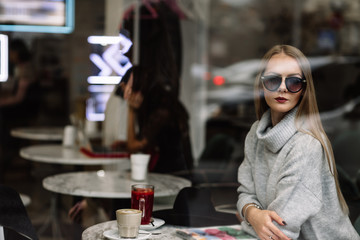portrait of a young beautiful fashionable woman wearing sunglasses. A model in a stylish wide-brimmed hat. Harmoniously similar clothes in gray tones. Uleach style of shooting. Women's fashion.