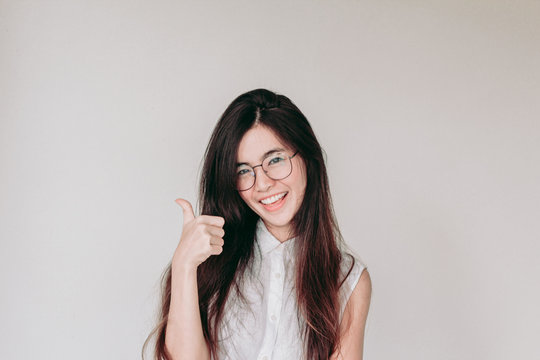 Head shot of Young cute asian student wearing glasses and smiling with thumb up
