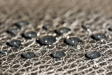 dark round drops of water on the embossed surface of black leather, macro background