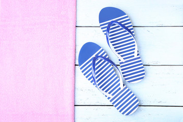 Pair of flip flops with towel on wooden table