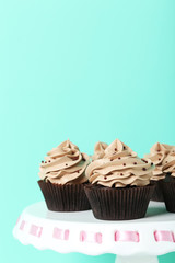 Tasty cupcakes on cake stand on green background