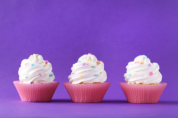 Tasty cupcakes on a purple background