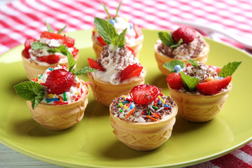 Dessert tartlets with strawberries in plate on wooden table