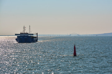 Cargo ship at sea on a background of Crimean bridge