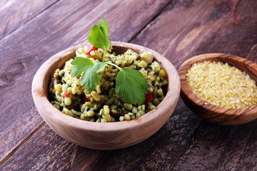 Bowl with homemade Bulgur Salad on wooden background.