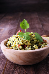 Bowl with homemade Bulgur Salad on wooden background.