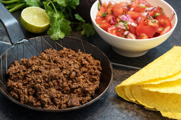 fried ground beef in a pan, as a filling for taco shells with ingredients as tomato salsa, lime and...