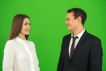 The happy businessman and businesswoman stand on the green background