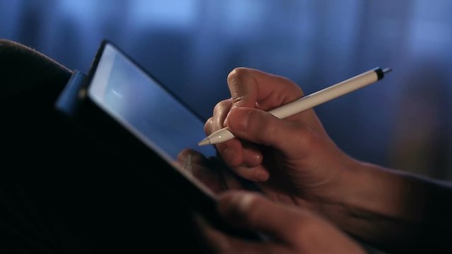 Closeup shot of designer's hand drawing a picture using tablet with stylus at home. Artist make work. Painter is sketching.