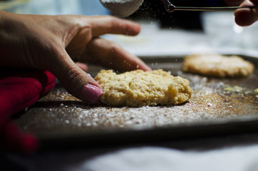 Food shown through baking, cookie on plate for dessert.  Shows prep with woman's hand and powdered sugar.