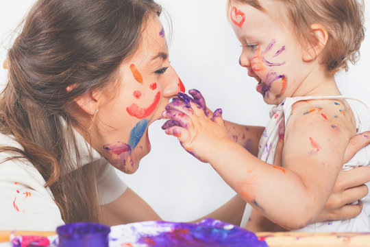 Happy mom and baby playing with painted face by paint