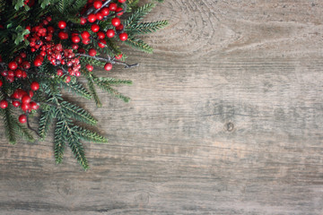 Christmas Evergreen Branches and Berries in Corner Over Rustic Wood Background