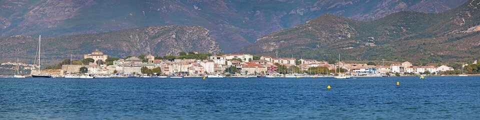 Fototapeta na wymiar Corsica, 29/08/2017: lo skyline di Saint-Florent (San Fiorenzo), villaggio di pescatori sulla costa ovest dell'Alta Corsica chiamato la Saint-Tropez corsa, visto dalla spiaggia Plage de la Roya