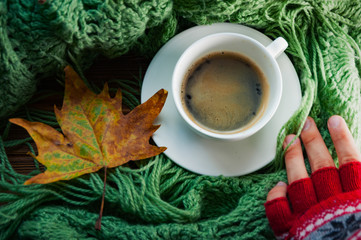 Human hands in red knitted gloves are holding the cup of hot coffee, top view, flat. Concept of autumn, warmness and comfort