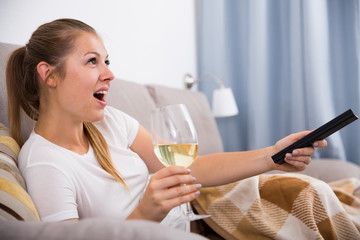 Girl is resting with wine and watching TV