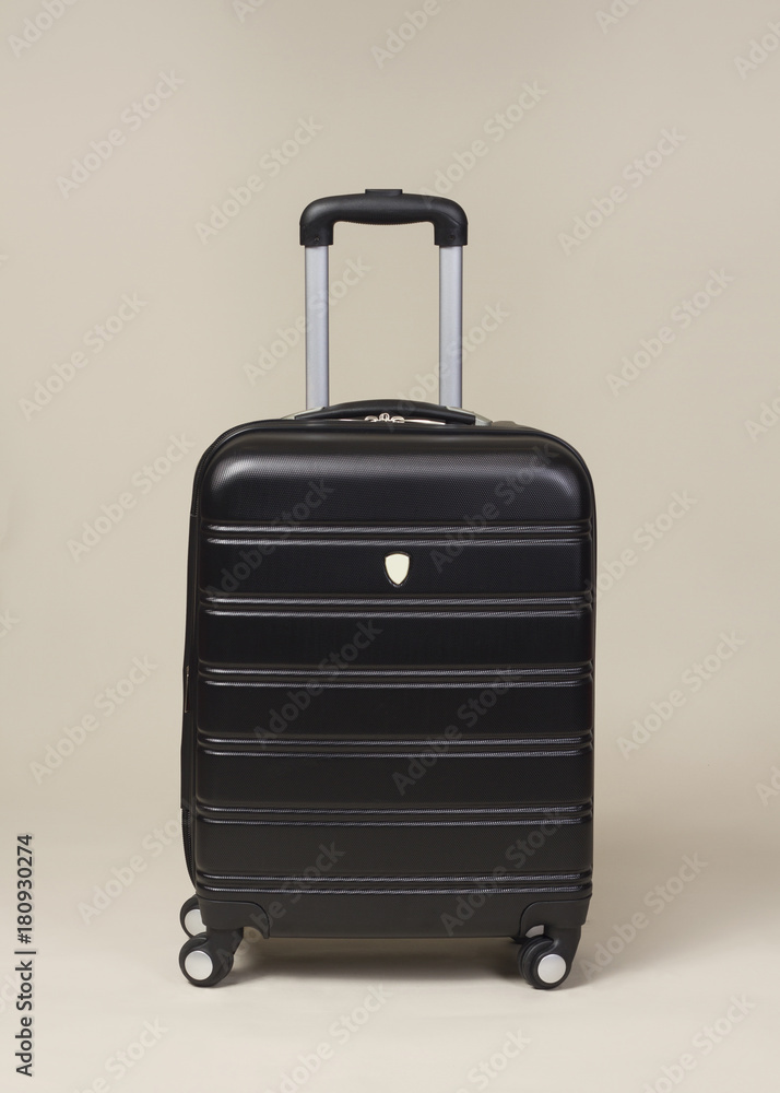 Wall mural black trolley suitcase bag isolated on beige background