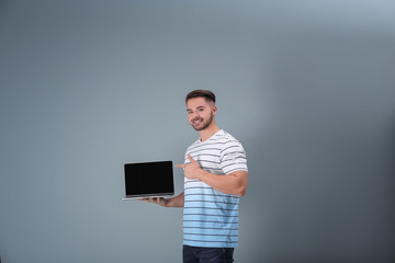 Young man with laptop against light background