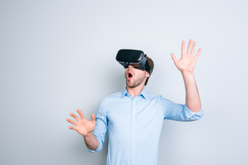 Close up of cheerful student in shirt wearing virtual reality goggles, getting experience using VR-headset of virtual reality, gesticulating, touching something with his  hands 