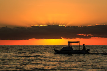 The silhouette of a boat and a fisherman at the sunset near Vrsar