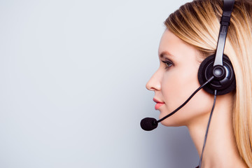 Half face side portrait of attractive blonde call center operator in a headset. She is isolated on...