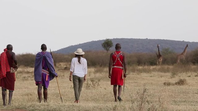 Tourist walks with tribesman across the savannah. 