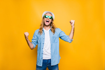 Yes! Lucky young hipster man isolated over yellow background, happy man wearing glasses and hat...